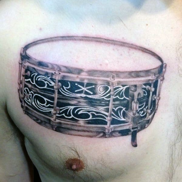 Snare Drum Tattoo On Mans Upper Chest With Decorative White Ink Design