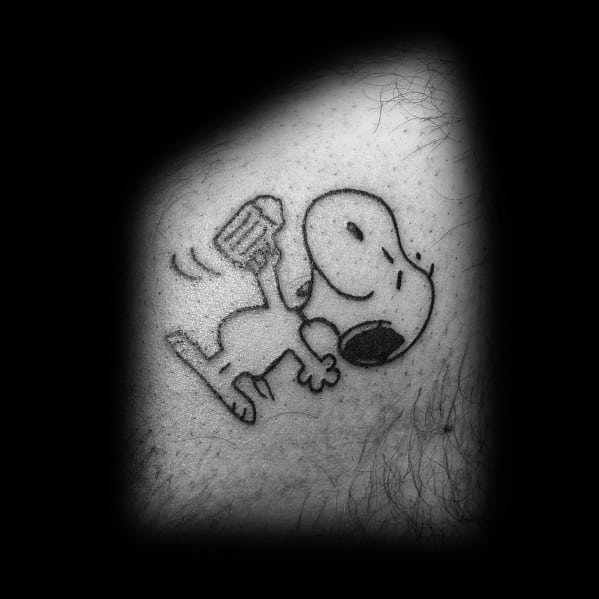 Black and white tattoo of Snoopy joyfully dancing while holding a frothy beer mug, with motion lines, placed on a person's skin.