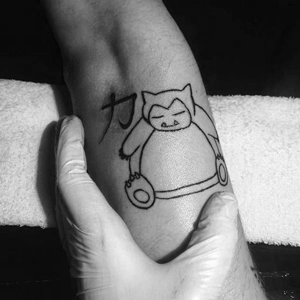 Minimalist Snorlax outline tattoo on leg with a Japanese kanji symbol beside it, featuring clean black linework.