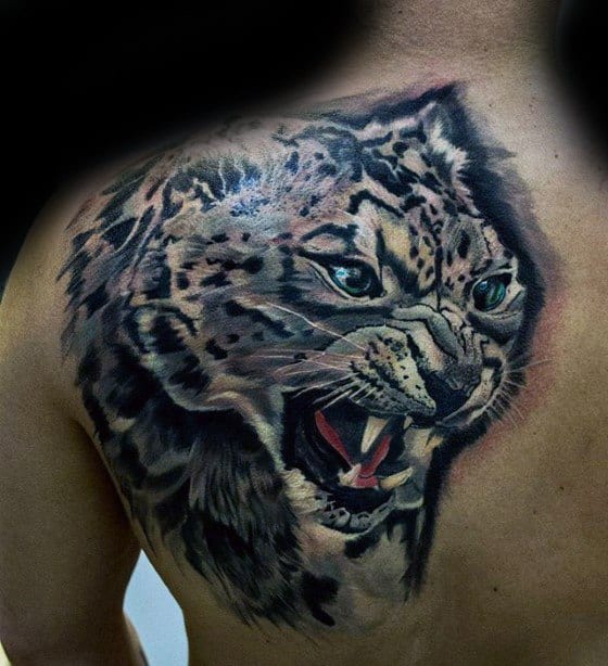 Realistic snow leopard tattoo on the shoulder, featuring vivid blue eyes, an open snarl, and dynamic shading for a powerful, lifelike look.