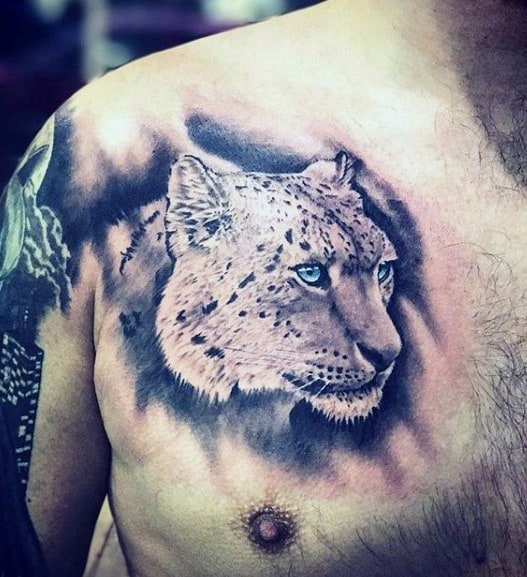 Realistic snow leopard tattoo on the chest with soft shading and vivid blue eyes, capturing the feline’s calm and powerful presence.
