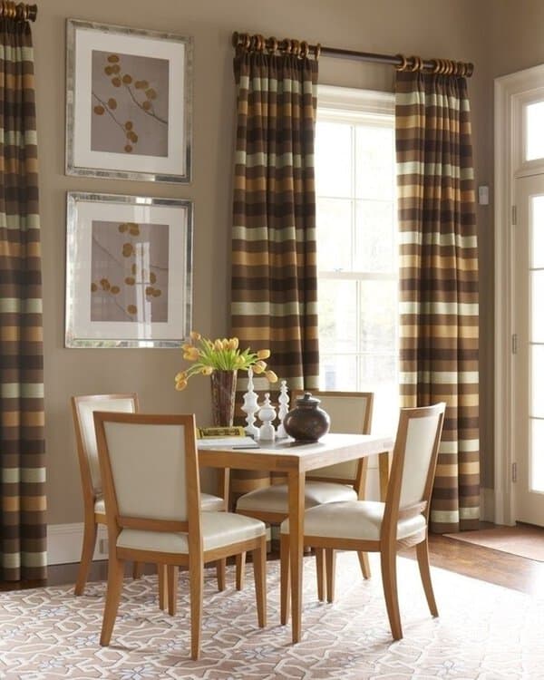 Warm dining room with striped brown curtains, wooden furniture, and elegant wall art.
