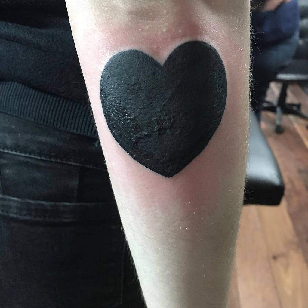 Large solid black heart tattoo featuring a deep, saturated ink design