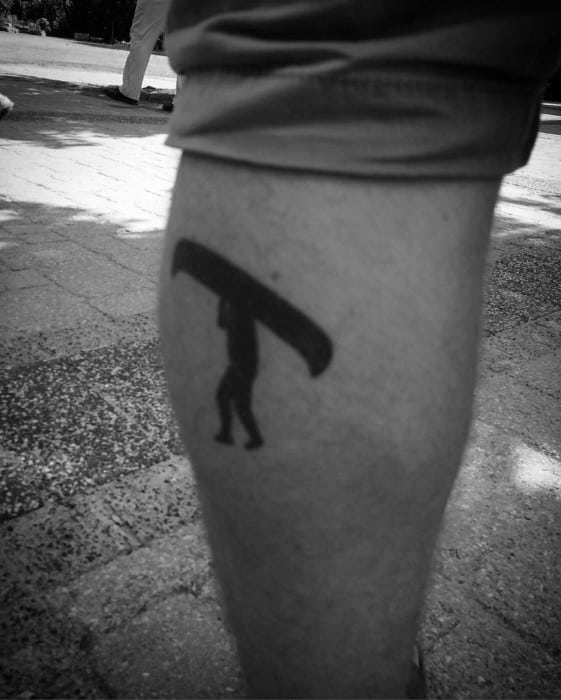 Alt text: Minimalist black tattoo of a person carrying a canoe, set against a simple background for a sleek and modern look.
