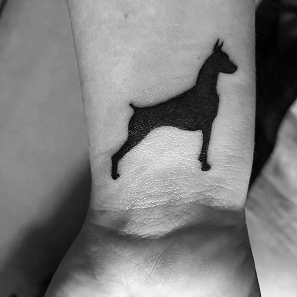 Minimalist Doberman silhouette tattoo on the wrist, featuring a bold black outline of the dog in a strong, upright stance.