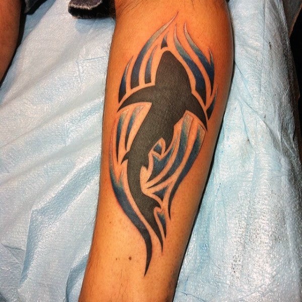 Solid Black Shark Tattoo On Mans Inner Leg With Tribal Wave Design