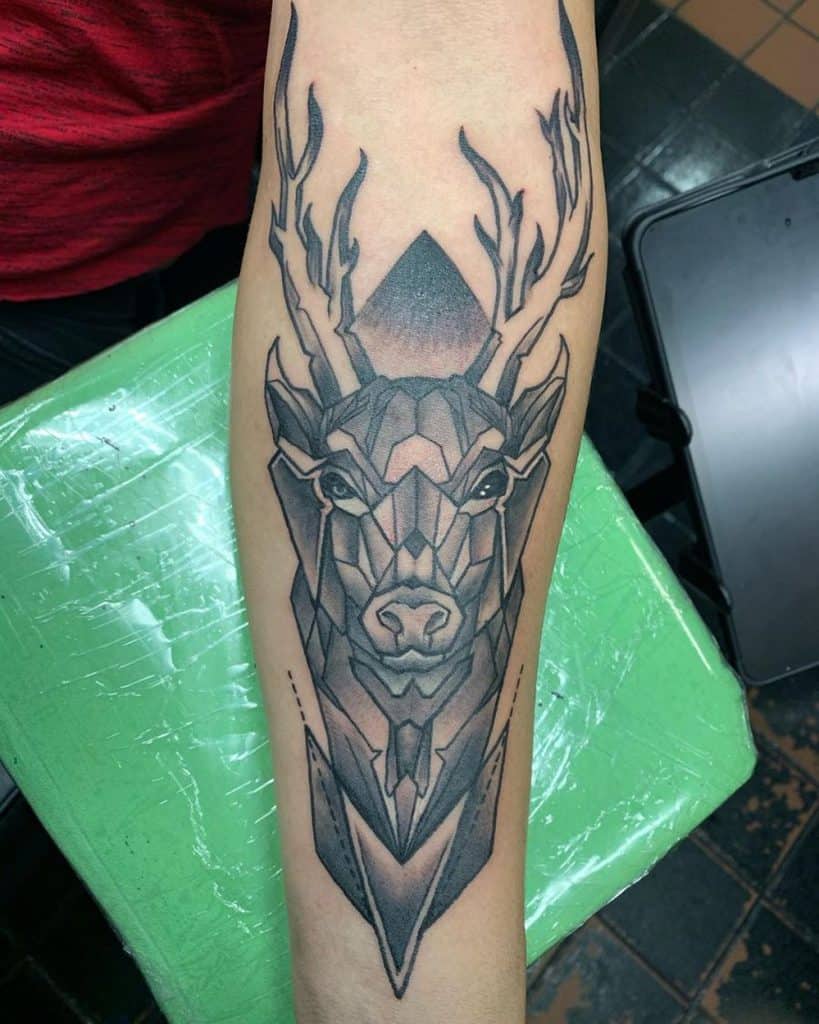 Forearm tattoo of a geometric stag with bold shading and sharp angular details, creating a modern and powerful design.