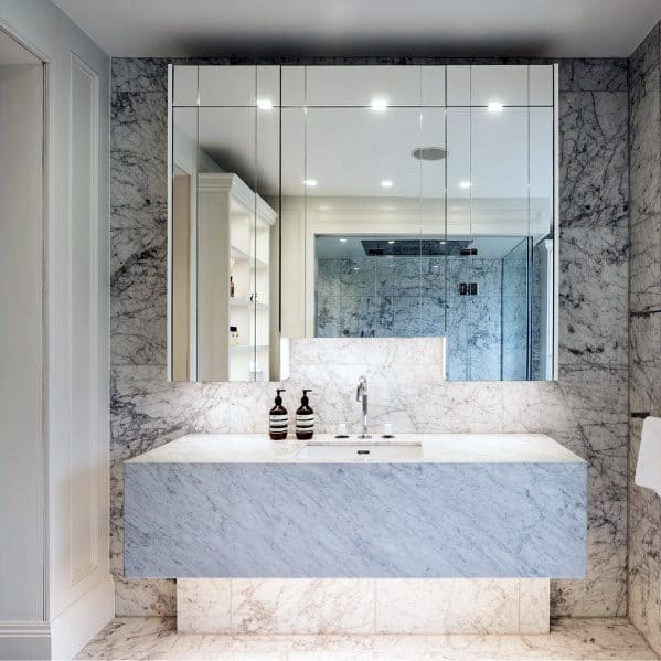 Modern floating marble vanity with mirrored cabinet and recessed lighting.