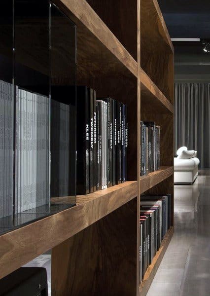 Wooden bookshelves filled with books, with a glimpse of a white couch in a modern interior