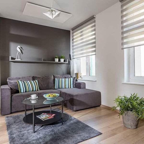 Modern grey and white living room with a sectional sofa, striped pillows, and sleek decor.