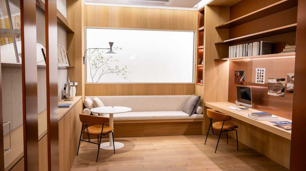 Modern workspace with built-in shelves, cozy seating, and compact desk setup.