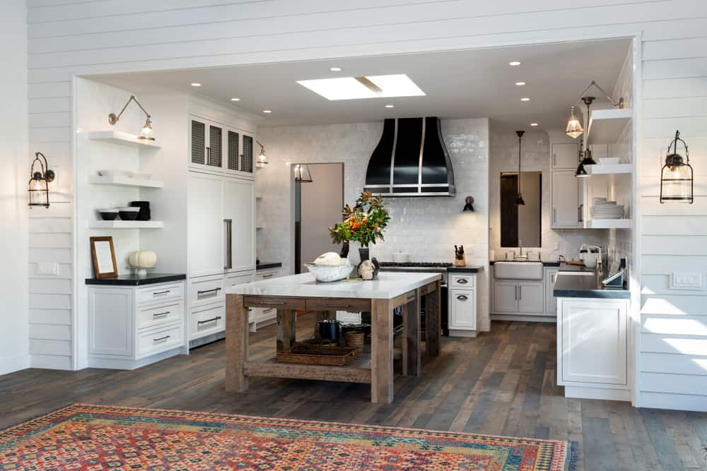 spacious farmhouse kitchen white cabinets wood table pattern floor rug hardwood floors