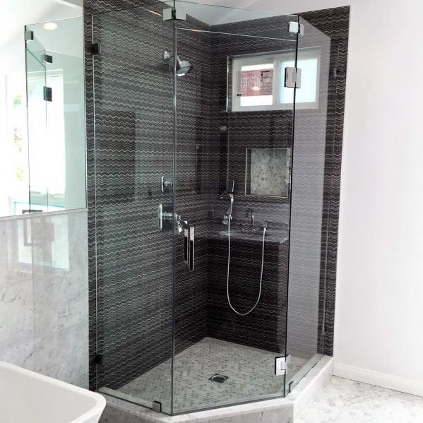 Corner glass-enclosed shower with sleek black tile and modern fixtures in a bright bathroom