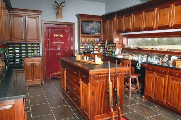 Spacious gun room with elegant wooden cabinetry, a reloading station, and a secure vault door.