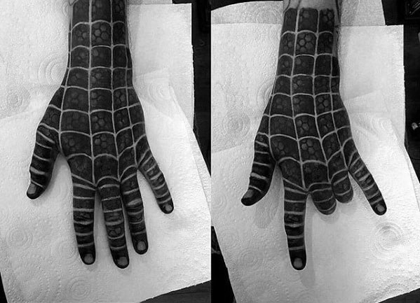 A person's hands with black and white geometric tattoo patterns, resembling a spiderweb, displayed on white paper towels