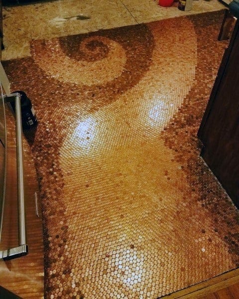 Penny tile floor with a swirling spiral design in copper shades for a unique decorative touch.