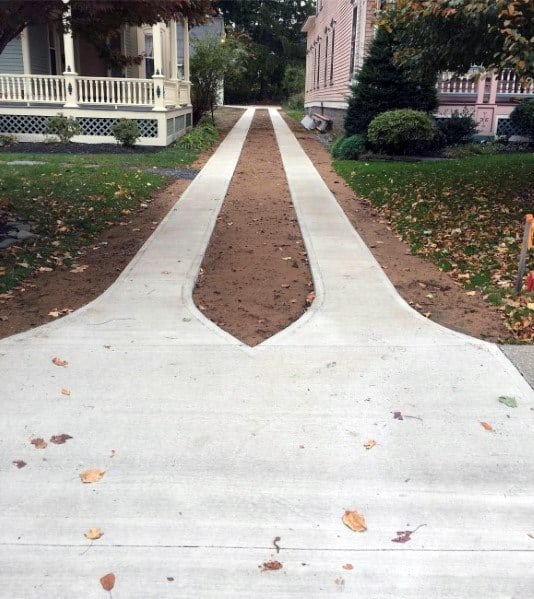 A split concrete driveway with parallel tracks, leaving a central strip of soil for landscaping or grass.