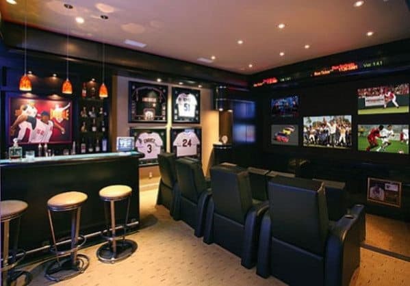 Home theater with sports memorabilia, bar seating, and multiple screens showing live sports events