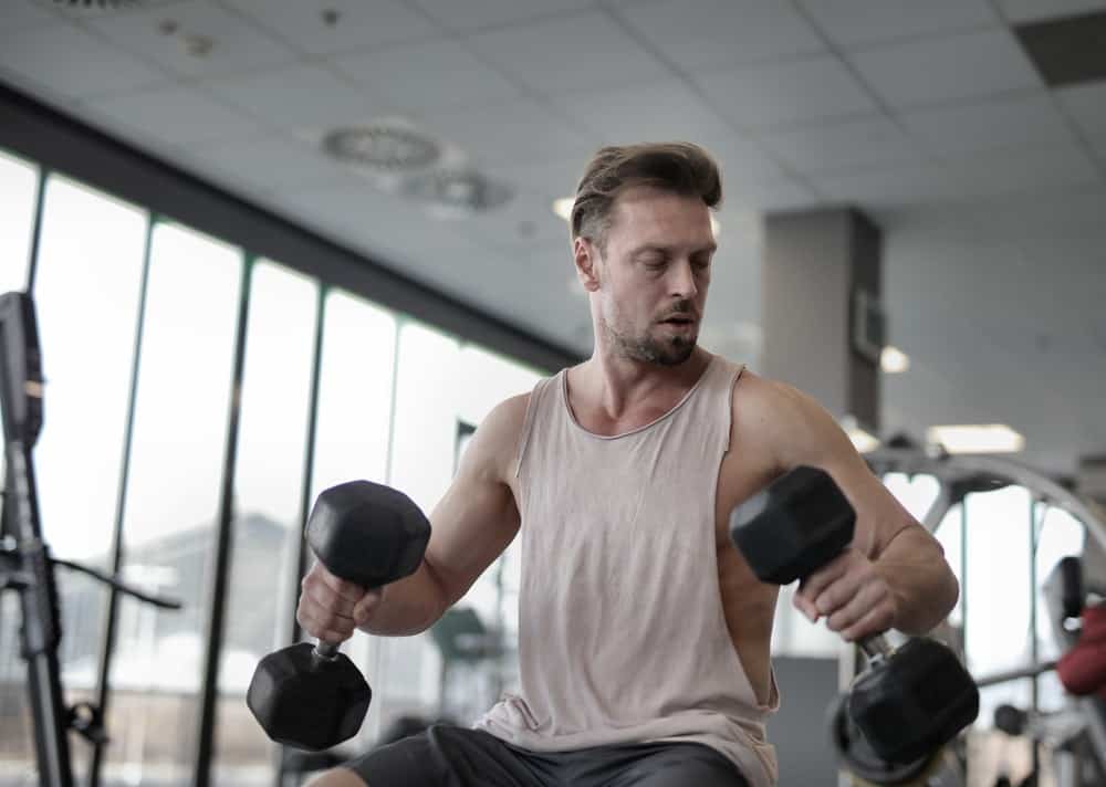 sportsman exercising with black dumbbells in gym