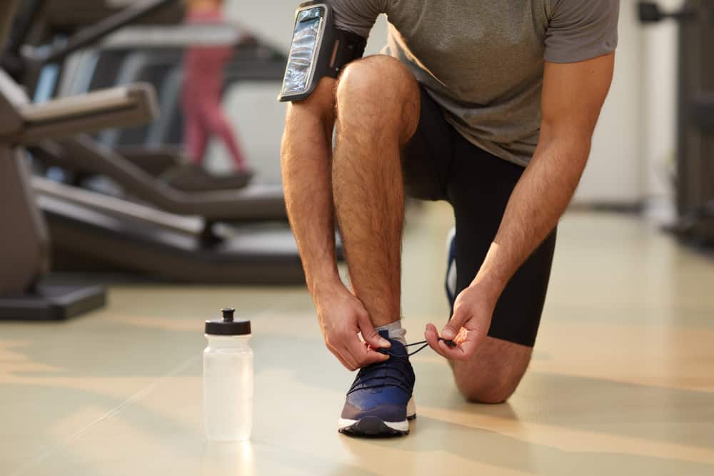 sportsman tying laces of blue shoes