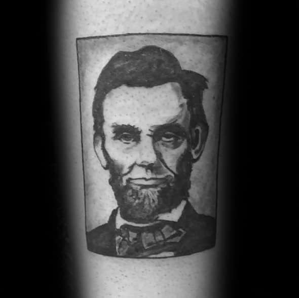 Framed black and white tattoo of a bearded man in a suit with a bow tie, reminiscent of Lincoln