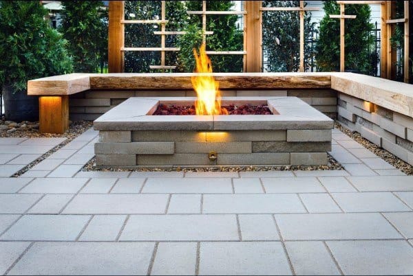 A modern patio featuring a sleek fire pit, surrounded by cozy seating and lush greenery