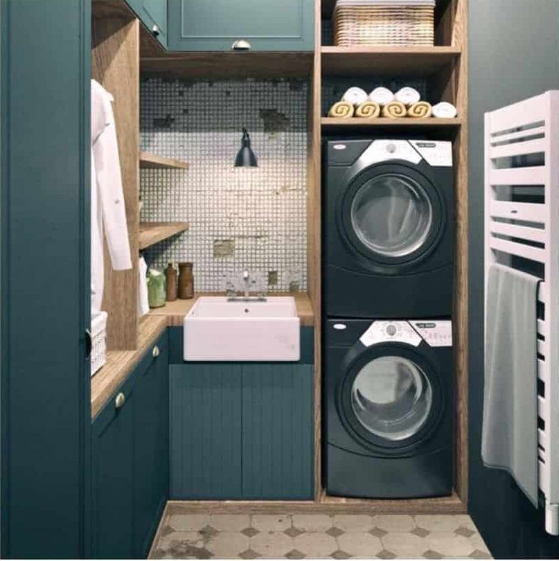 stacked stacked washer and dryer in green cabinet laundry room with apron sink