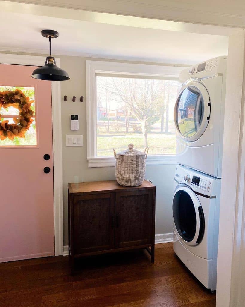 country style laundry room with wood cabinet and pink door