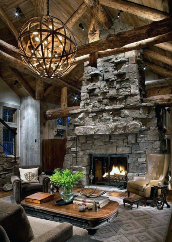 Rustic living room with stacked stone fireplace, exposed wooden beams, and globe chandelier.
