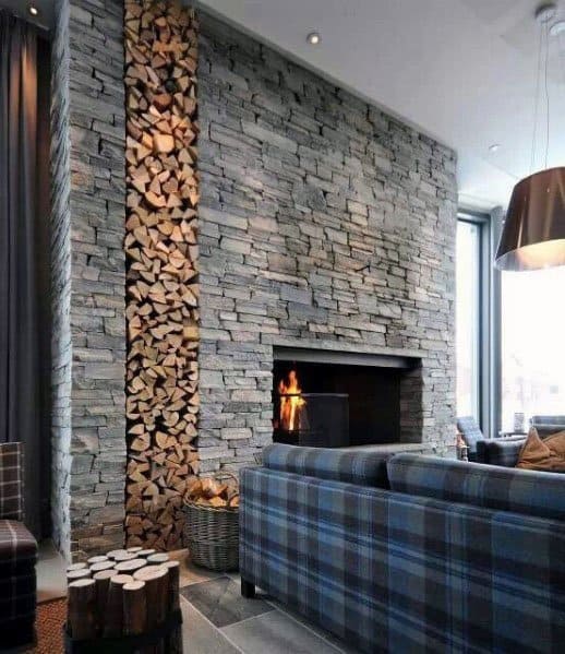Modern living room with a stacked stone fireplace, stacked firewood, and plaid furniture