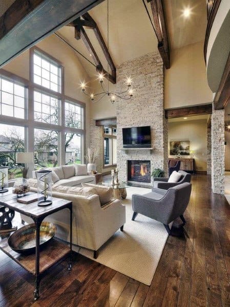 Spacious living room with high ceilings, wooden beams, and a cozy stacked stone fireplace