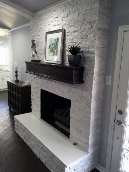 Stacked stone fireplace with dark wood mantel, decorated with a picture and small plant