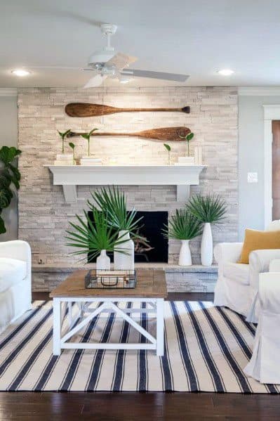Stylish living room with oars on stacked stone wall, white seating, and striped rug