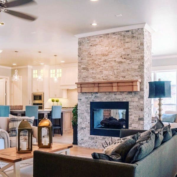 Cozy living room with stacked stone fireplace, modern kitchen, and elegant lighting