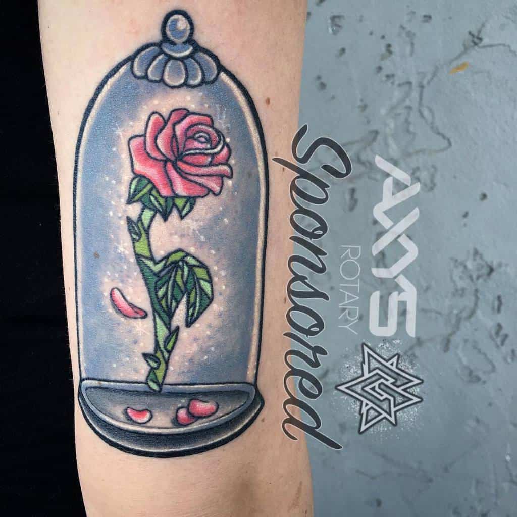 A vibrant Beauty and the Beast rose tattoo featuring a pink rose in a glass dome, with soft highlights and scattered petals around the base