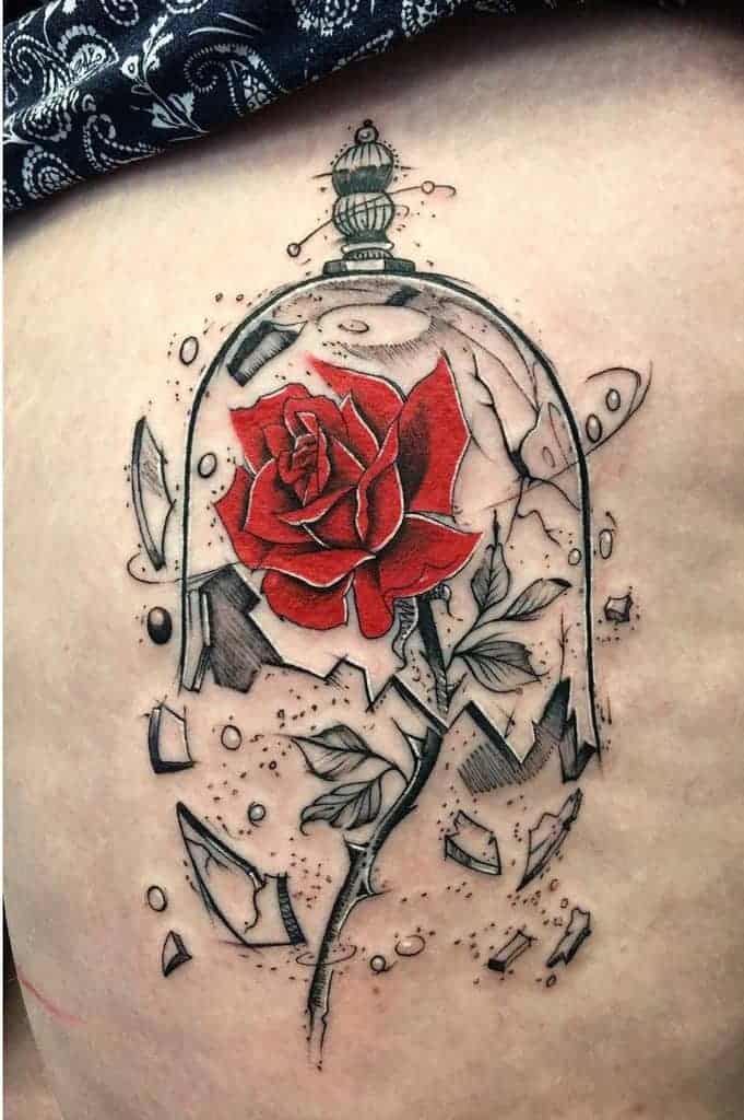 Creative tattoo of a red rose under a shattered glass dome, combining bold red petals with detailed black and gray shading