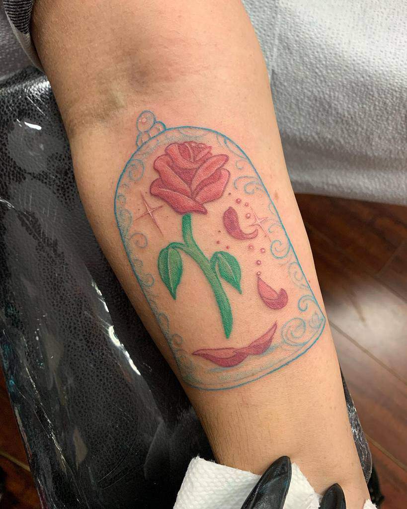 Tattoo of a red rose under a glass dome, inspired by "Beauty and the Beast"