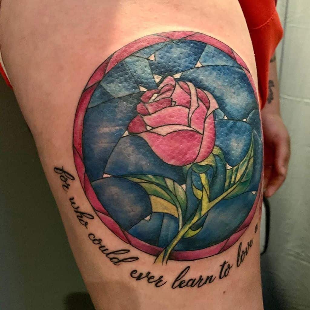 A Beauty and the Beast-inspired tattoo of a pink rose inside a stained glass dome with the quote "for who could ever learn to love a beast" beneath it