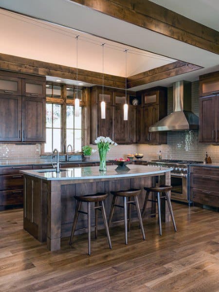 Rustic kitchen with dark wood cabinets, stainless steel appliances, pendant lights, and hardwood floors.