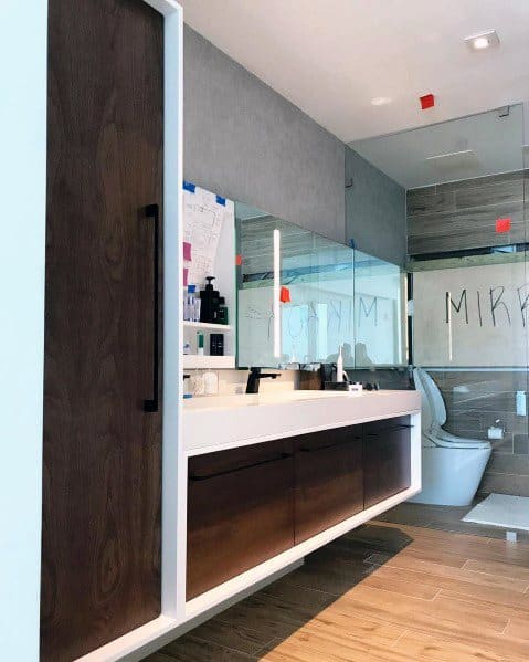 Modern bathroom with stained wood vanity, large mirror, and glass-enclosed shower.