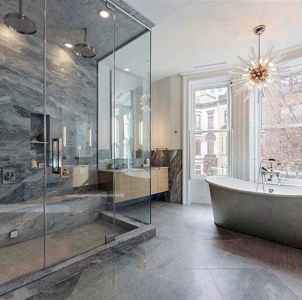 Modern bathroom with freestanding tub, glass shower, and starburst crystal chandelier.