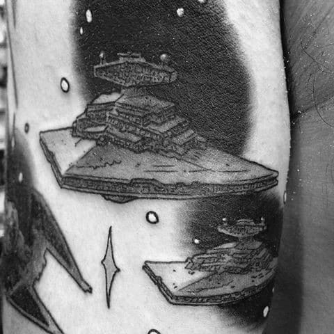 Black and gray tattoo of multiple Star Destroyers floating in deep space, with stars and shadows adding depth and contrast.