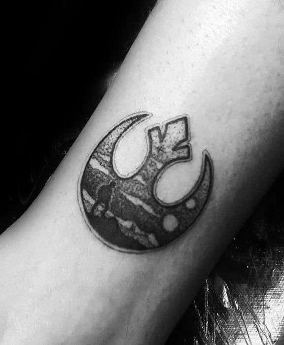 Small black and gray Rebel Alliance tattoo on the forearm, featuring a desert landscape and a lone figure