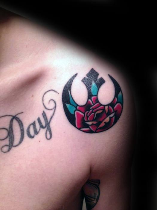 Tattoo of a rose inside a Rebel Alliance symbol on shoulder, next to tattooed letters "Day