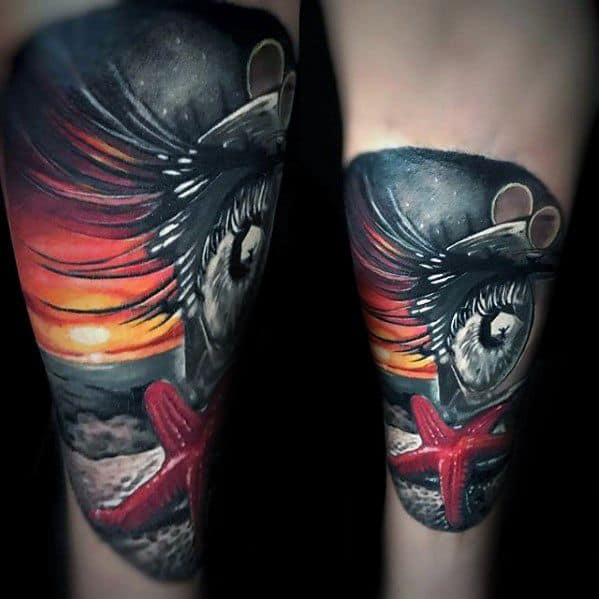 Vivid forearm tattoo featuring a red starfish, a realistic eye, and a dramatic sunset, blending surrealism with ocean elements.