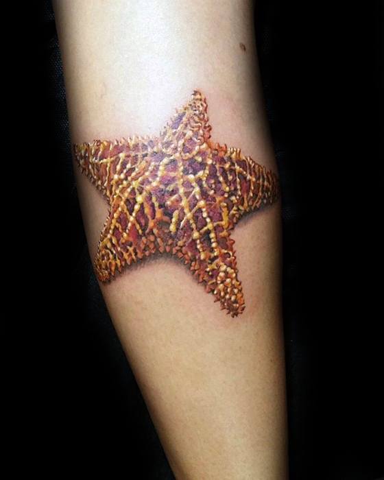 Hyper-realistic orange starfish tattoo on the forearm with textured spikes and lifelike shading, creating a 3D effect.