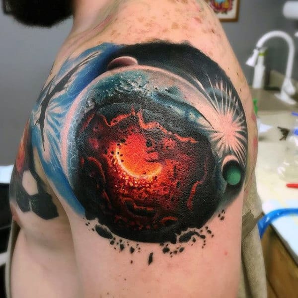 Colorful space-themed tattoo on a person's shoulder featuring a fiery planet and space
