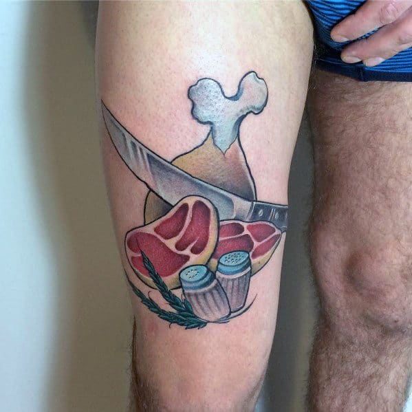 Tattoo of a steak, chicken drumstick, knife, salt and pepper shakers, and herbs, creating a bold and detailed food-themed design.