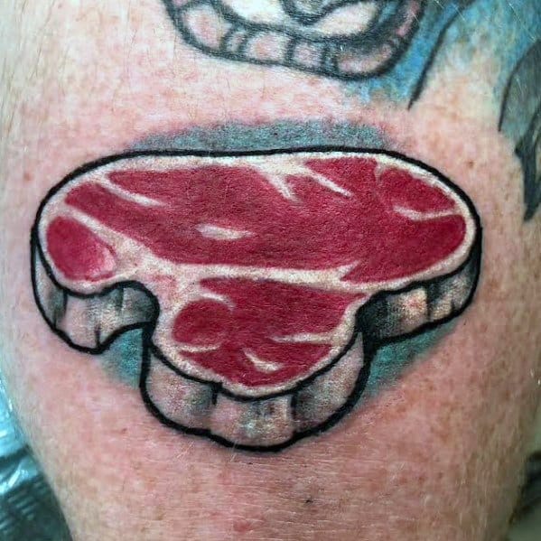 Tattoo of a raw steak with thick black outlines and bold red shading, designed in a stylized cartoon-like shape for a playful and eye-catching look.