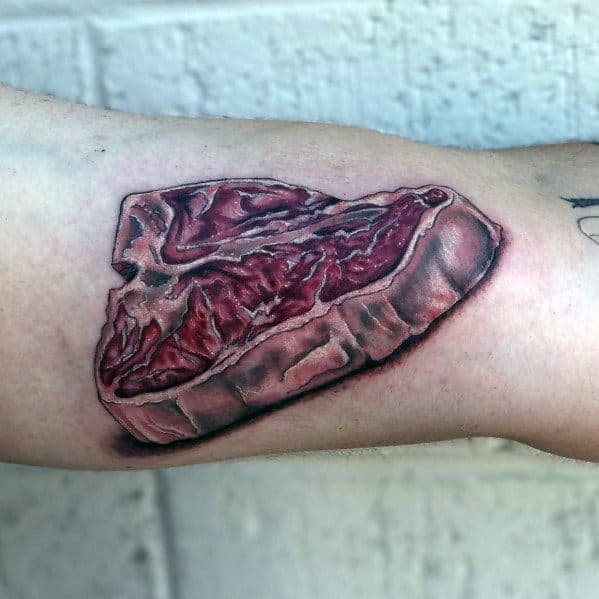 Tattoo of a highly detailed and realistic raw steak with rich marbling and shading, creating a bold and lifelike meat-inspired design.